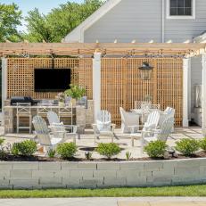 Hamptons-Inspired Outdoor Kitchen and Dining Room With Trellis and Fire Pit 