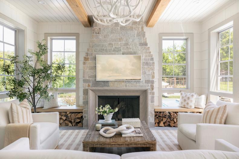White room with pale stone fireplace and windows.