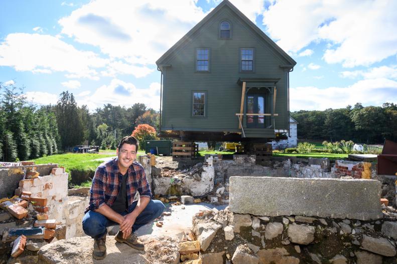 Jonathan Knight in front of his lifted New England farmhouse, prior to it being moved down the road, as seen on Farmhouse Fixer.