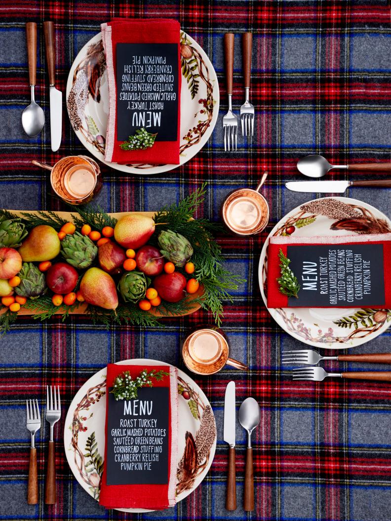 This woodsy table display features a plaid tablecloth, copper mugs and a rustic fruit bowl.