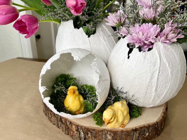 Add dry rice, beans or small rocks to the inside of the egg to keep it from rolling or tipping over. Find a jar or vase that is small enough to fit inside the egg without being seen. Make sure to cut the flowers long enough, so they pop out of the egg. Arrange them in the jar or vase and fill the water half way. Place the flowers in egg and arrange with other eggs and easter embellishments.