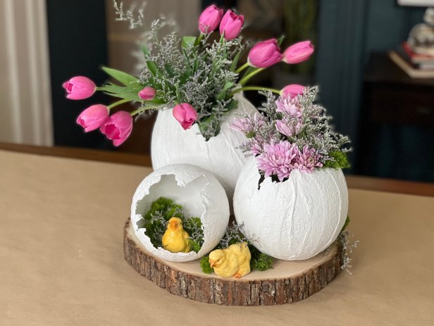Add dry rice, beans or small rocks to the inside of the egg to keep it from rolling or tipping over. Find a jar or vase that is small enough to fit inside the egg without being seen. Make sure to cut the flowers long enough, so they pop out of the egg. Arrange them in the jar or vase and fill the water half way. Place the flowers in egg and arrange with other eggs and easter embellishments.