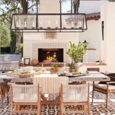 Mediterranean Outdoor Dining Room With Fireplace and Wrought Iron Candelabra