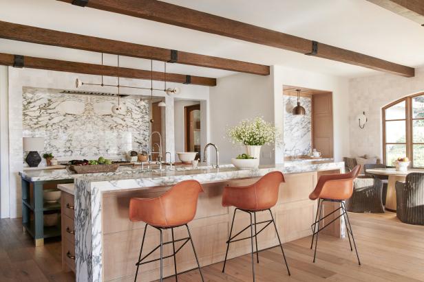 White kitchen with marble island and backsplash and leather barstools.