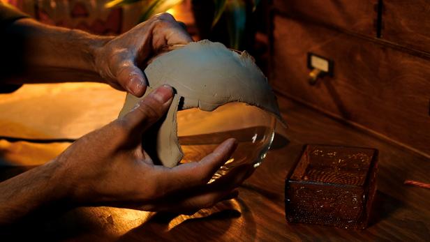 Dip your fingers into water to smooth out the edges of the clay and create a seamless look. Then, cut two thin strips of clay and add them to the top and bottom of the globe to create an eye shape. Once the strips are in place, smooth them with wet fingers to soften the edges.