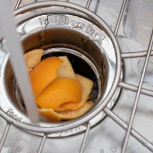Orange peels placed in a sink drain to clean a garbage disposal.