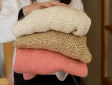 Woman Holding Stack Of Warm Sweaters