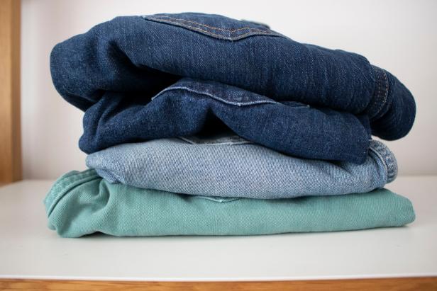 Four pairs of denim jeans in a folded stack.