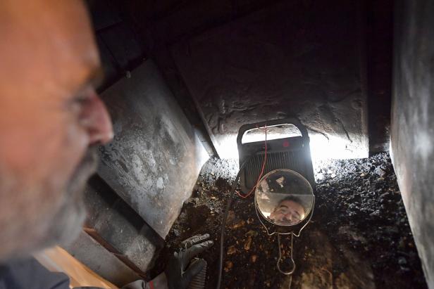 A heating engineer controls the flue of a wood-burning fireplace with the help of a mirror after cleaning it, in Illiers-Combray, central France on October 6, 2022. (Photo by JEAN-FRANCOIS MONIER / AFP) (Photo by JEAN-FRANCOIS MONIER/AFP via Getty Images)