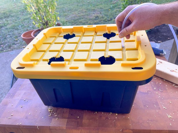 The next step in this DIY hydroponic garden is to slide the air hose through the hole in the plastic lid.