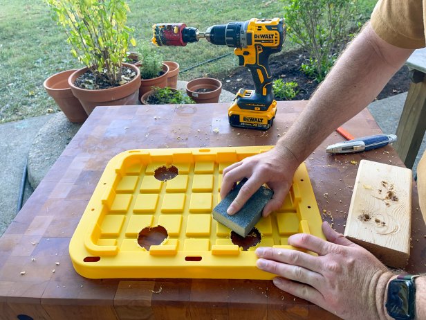 The next step in this DIY hydroponic garden is to clean up the splintered plastic around the holes using a sanding block.