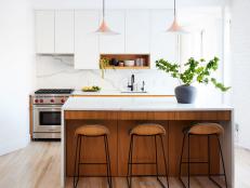 This kitchen features an island with white oak and marble countertop.