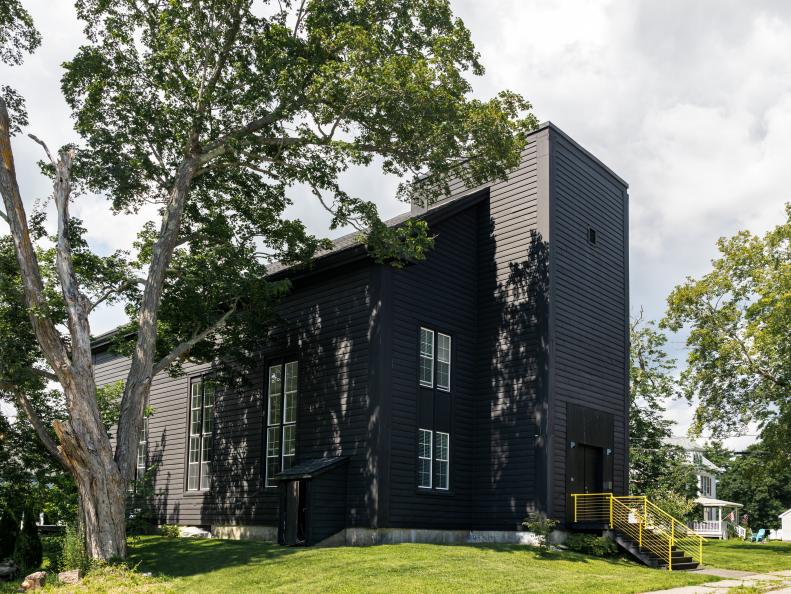 Two-story black building with long, thin windows and yellow rail.