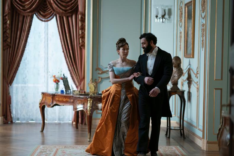 A man and woman arm and arm in a Victorian drawing room. 