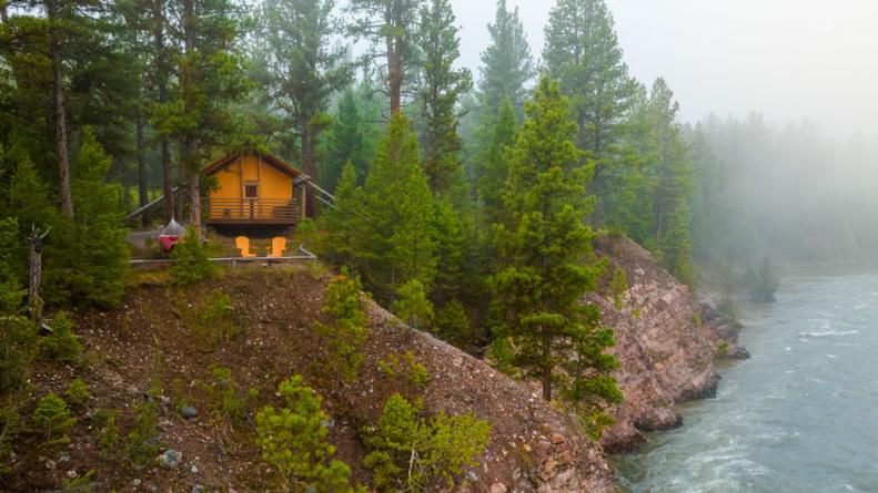 A glamping tent surrounnded by trees and overlooking a river at The Resort at Paws Up in Montana