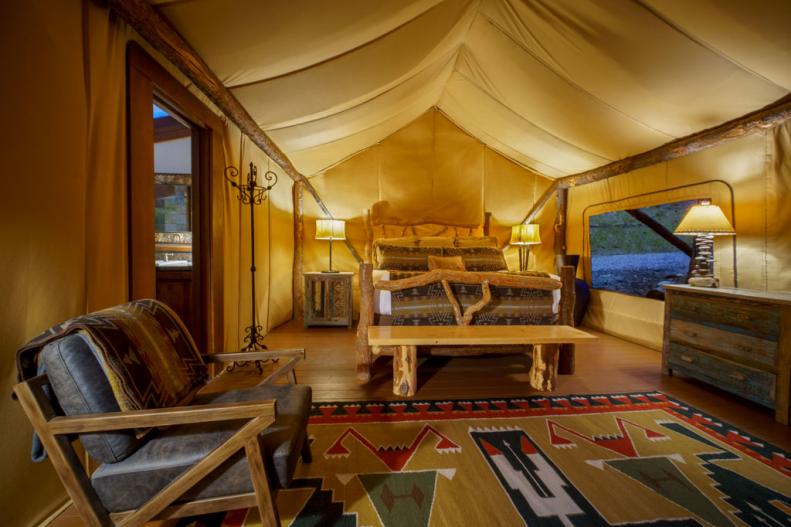 An interior view of a glamping tent, with a bed, side tables, lamps and other furnishings, at the Resort at Paws Up in Montana