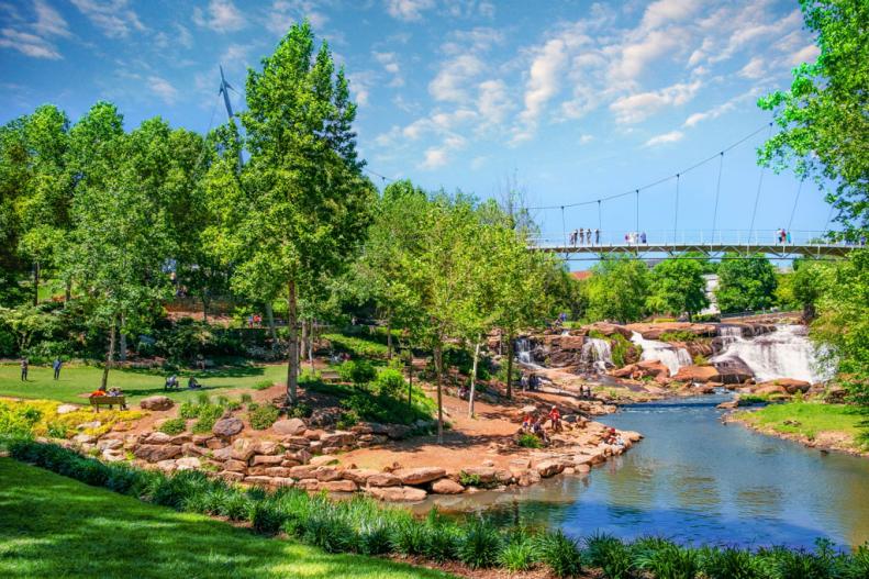 A view of the bridge, waterfalls and visitors at Reedy Park in Greenville, SC