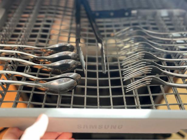 Flatware in a dishwasher's top rack.