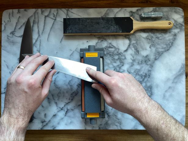 The next step in sharpening a knife on a sharpening stone is to start the sharpening motion on the desired starting grit, moving the heel of the knife to the tip.