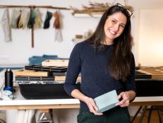 Woman smiles to camera holding handmade paper in her studio
