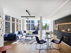 White open plan apartment with grey kitchen and blue accents. 