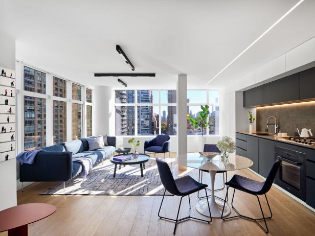 White open plan apartment with grey kitchen and blue accents. 