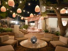 A patio lit by overhead string lights, lanterns, ground level accents lights and lights under steps.
