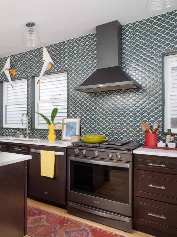 This blue-green kitchen from HGTV Magazine features fish scale backsplash tiles, modern lighting and a red runner rug.