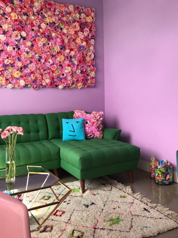 This fun living room from HGTV Magazine features purple-pink walls, a green sofa and a faux flower wall.