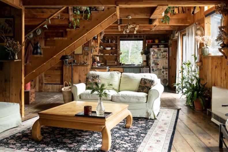 White sofas in wood cabin living room with large area rug, houseplants