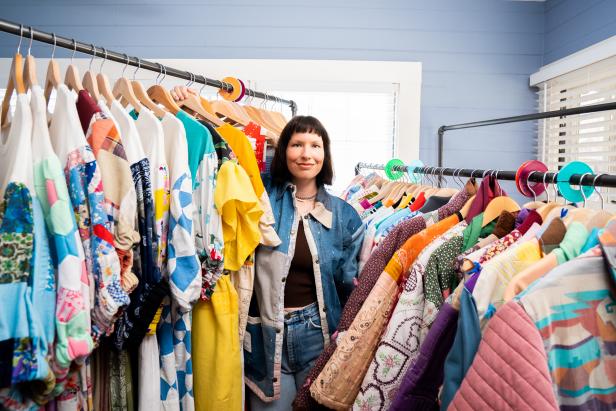 A woman stands between two clothing racks of quilted clothes.