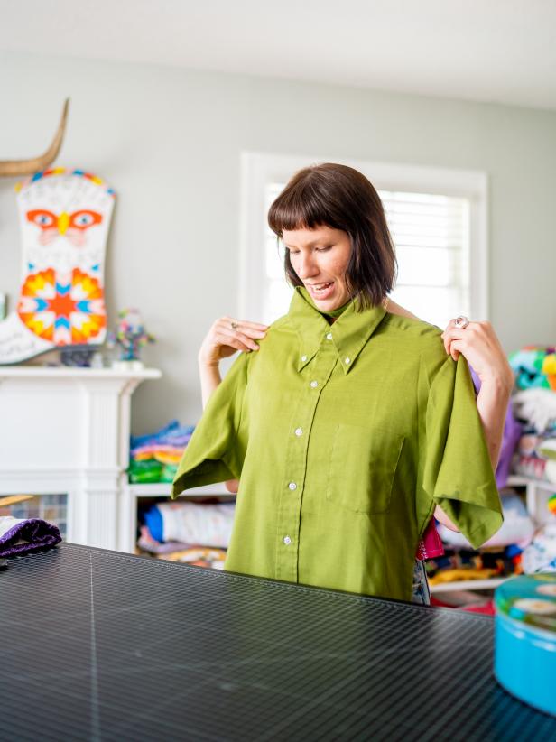 A woman holds up a men's vintage button-down shirt. 