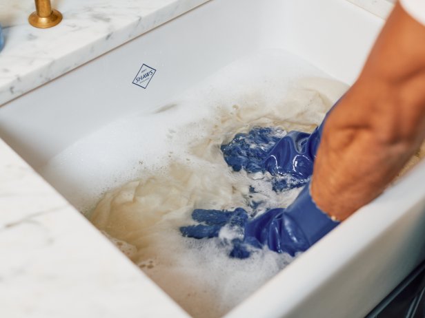 A Man Hand Washing a Sweater in a Sink