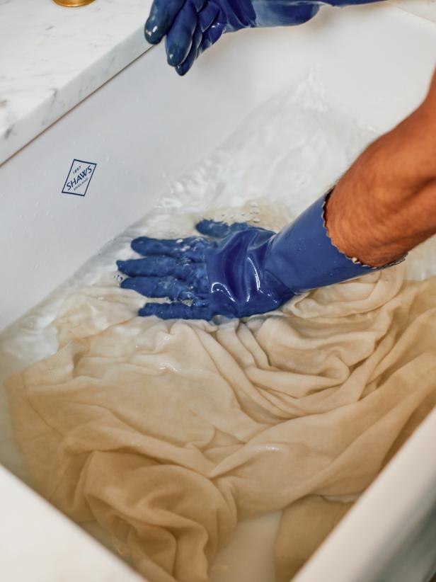 A Man Washing a Sweater With Blue Gloves