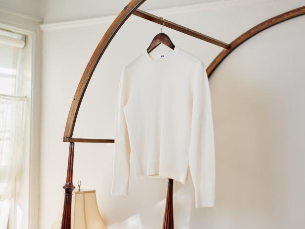 A White Wool Sweater Hanging on a Wooden Hanger