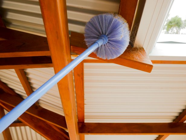 Cobweb brush sweeping spiderweb under the roof