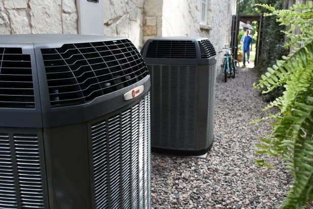 Two Trane heat pumps installed outside of a multi-family home.