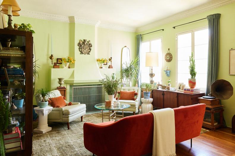 Green living room with fireplace, red vintage sofa and bookcase