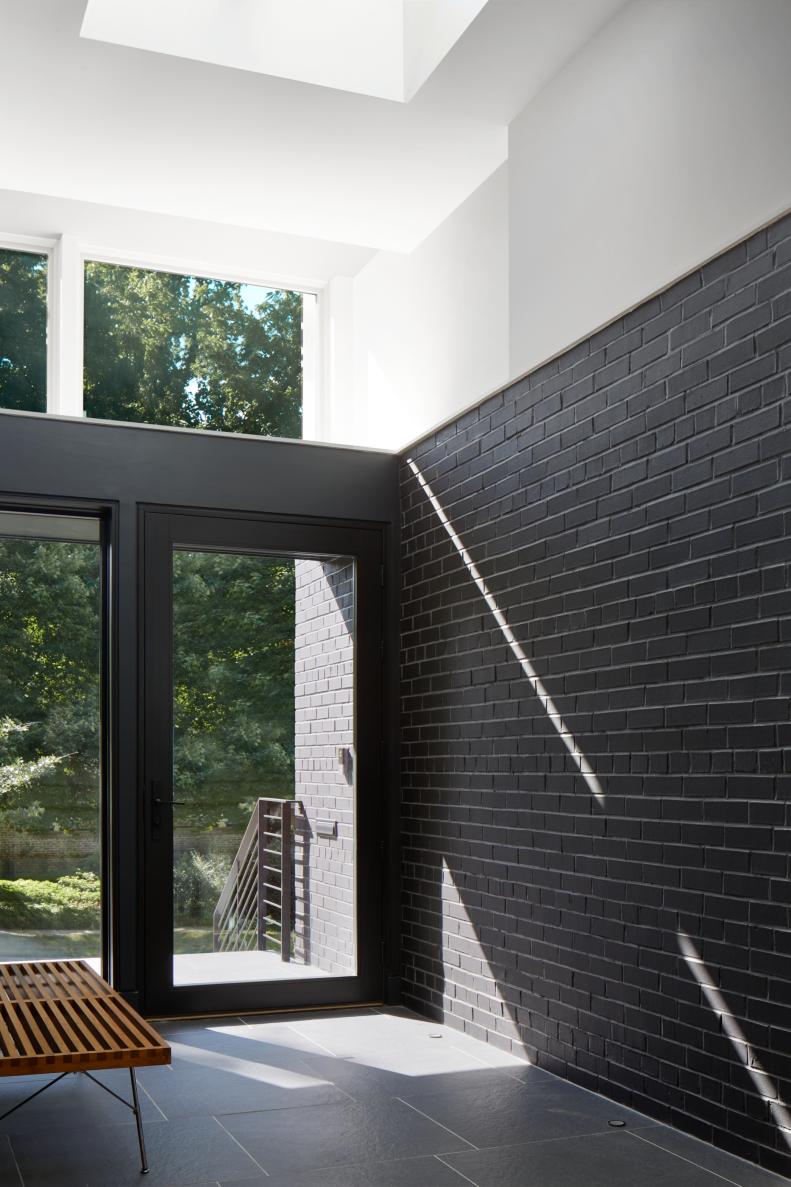 This foyer features a black brick wall and glass front doors.