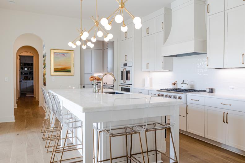 This white kitchen includes dramatic lighting and gold accents.