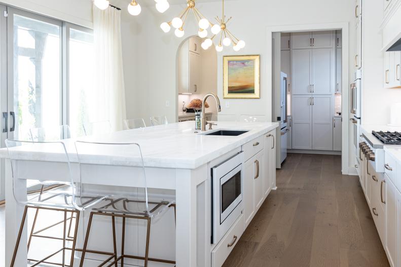 This all-white kitchen includes a dramatic gold chandelier.