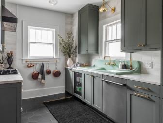 Farrow & Ball Green Smoke paint color paired with brass accents and a white Corian countertop gives this kitchen a timeless-meets-trending look.