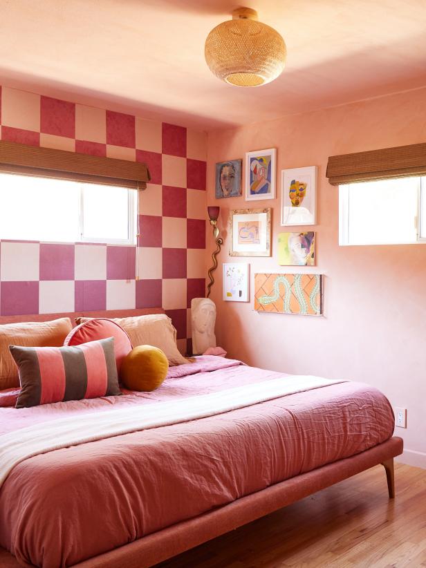 Pink bedroom with rattan lamp, checked wall and gallery art. 