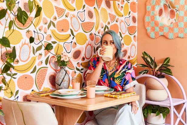 Woman with blue hair drinking coffee in colorful kitchen. 