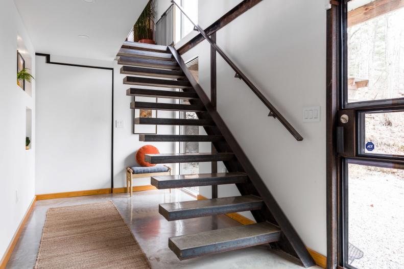 A white foyer with a cantilever concrete staircase leading up.