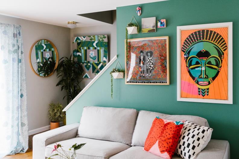 Living Room With Green Accent Wall and Colorful Art Over White Sofa