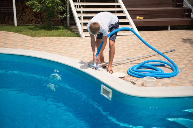 Man cleaning the swimming pool with vacuum cleaner 
