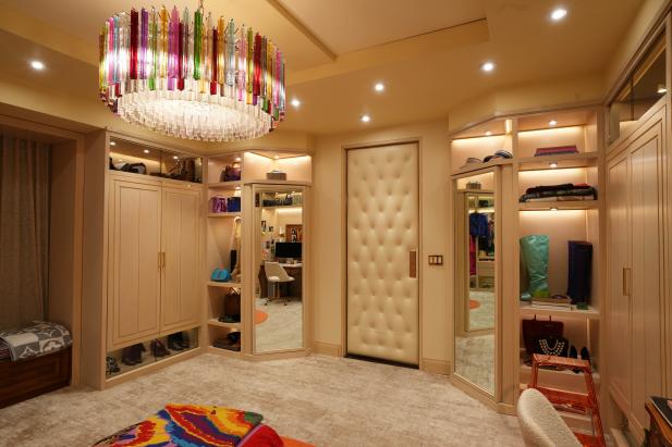 Walk-in closet with rainbow drum chandelier and colorful ottoman.