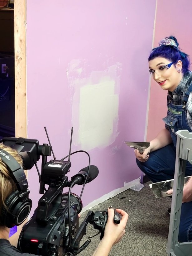 Woman Talks to Camera While Repairing Hole in Drywall