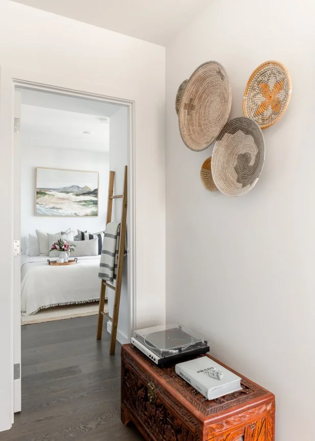 Entryway With Wooden Carved Chest and Large Straw Bowls as Wall Art